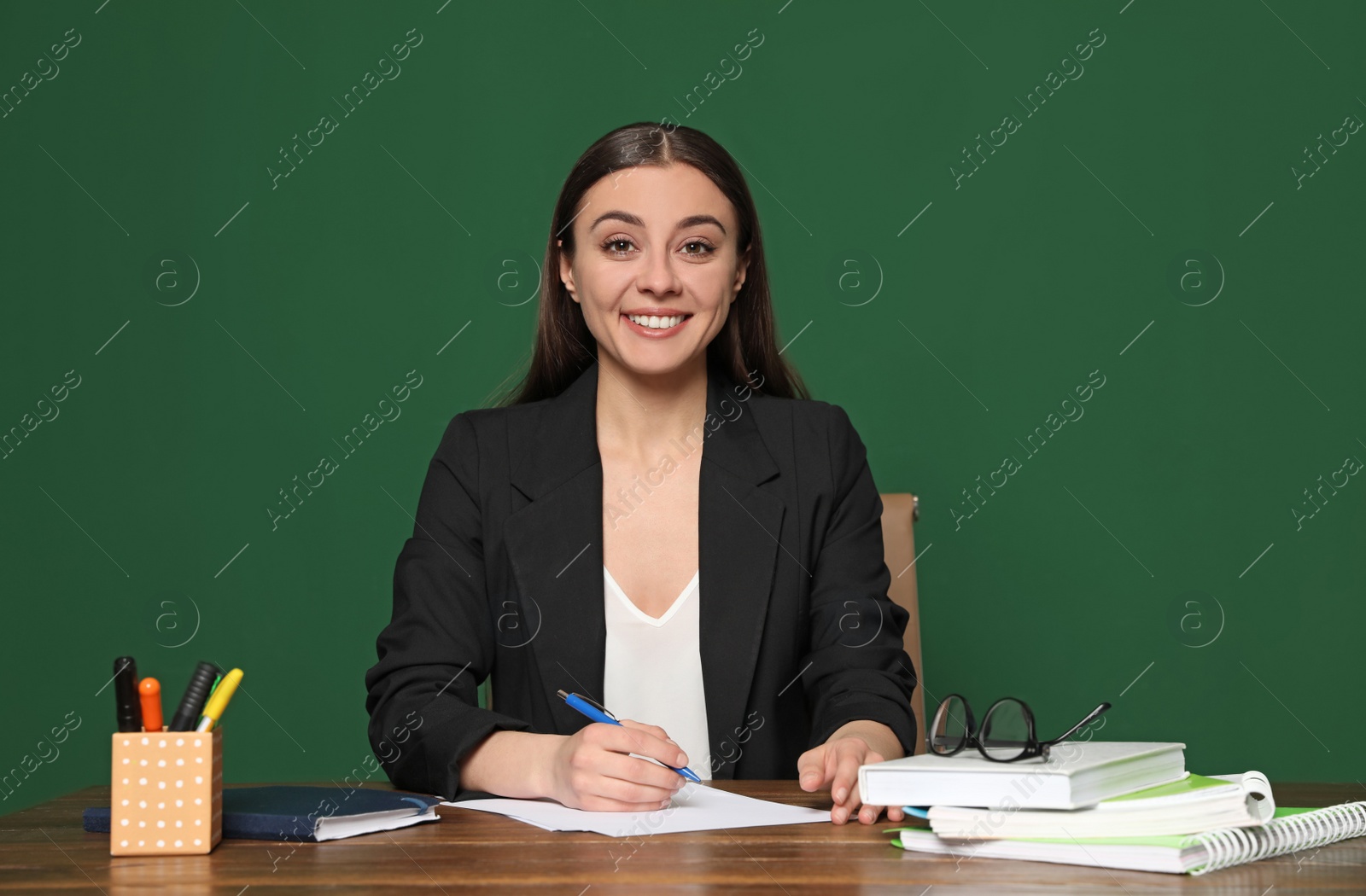 Photo of Portrait of young teacher at table against green background