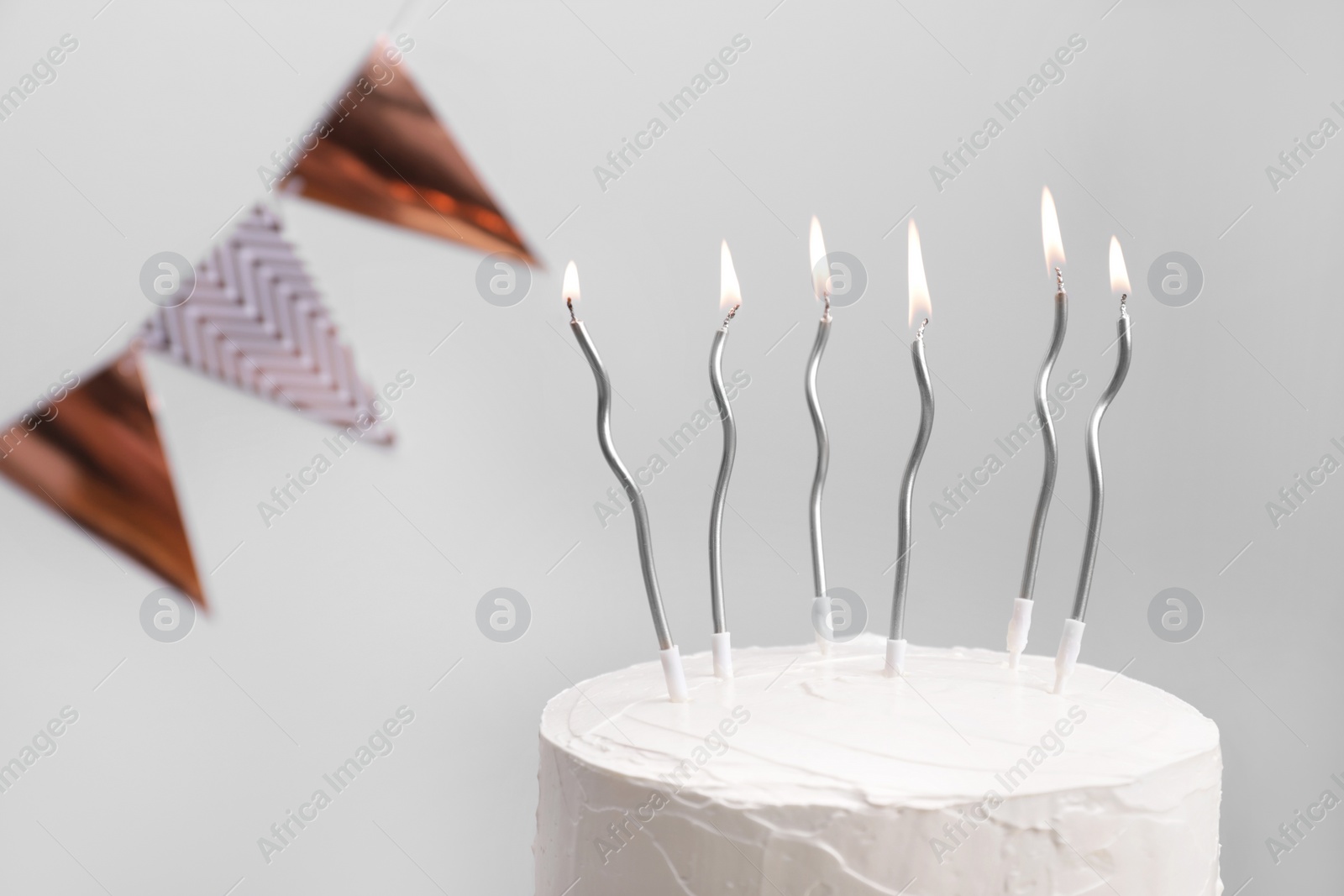 Photo of Delicious cake with cream and burning candles on light grey background, closeup. Space for text