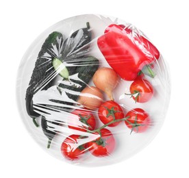 Photo of Plate of fresh vegetables wrapped with transparent plastic stretch film isolated on white, top view
