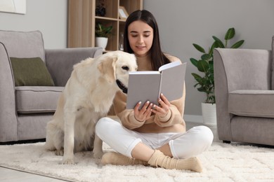 Woman reading book with cute Labrador Retriever dog at home. Adorable pet