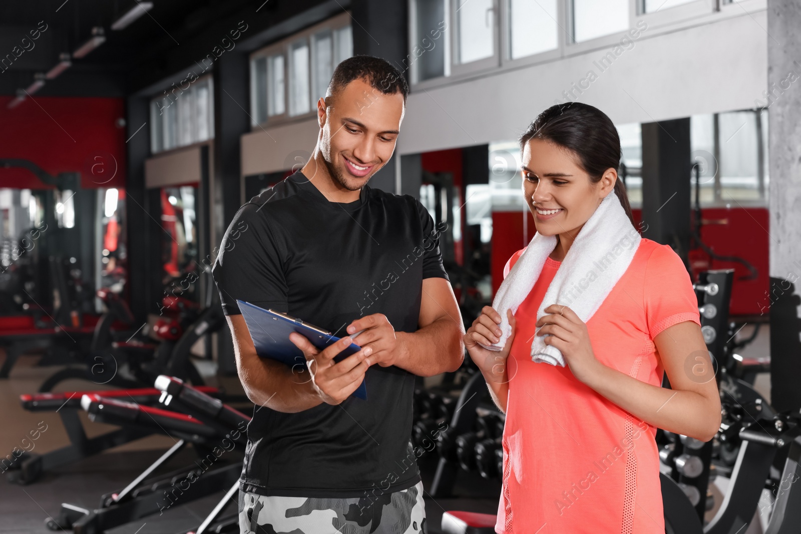 Photo of Happy trainer showing woman workout plan in modern gym, space for text