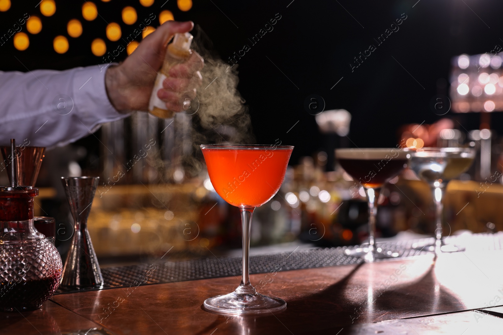 Photo of Bartender preparing fresh Martini cocktail in glass at bar counter, closeup