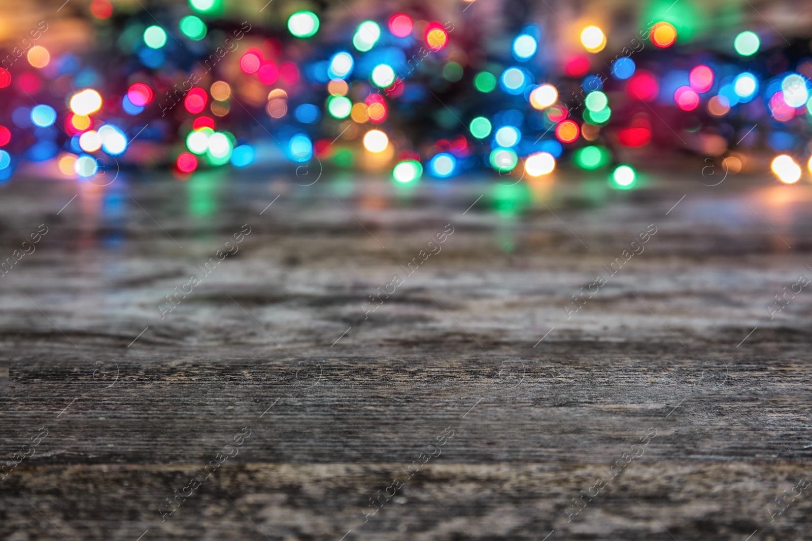 Photo of Wooden table and blurred Christmas lights on background