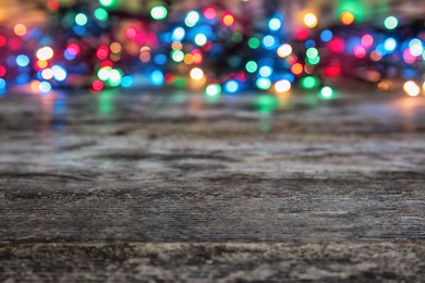 Photo of Wooden table and blurred Christmas lights on background