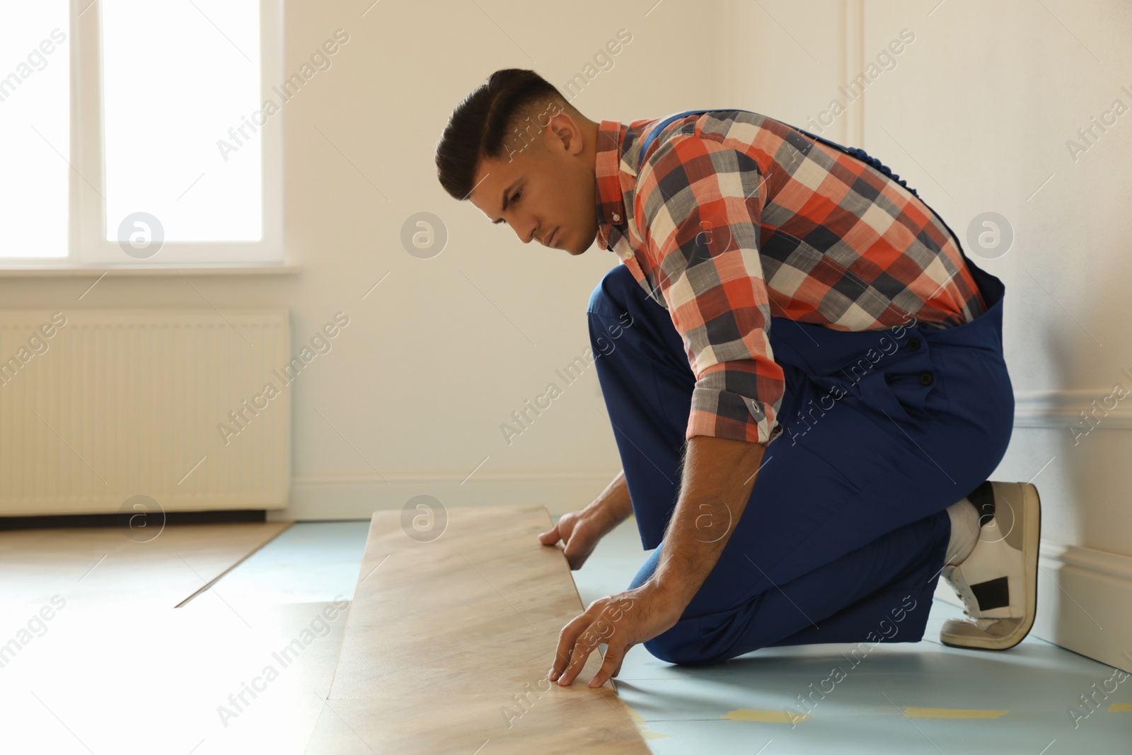 Photo of Professional worker installing new parquet flooring indoors