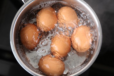 Photo of Chicken eggs boiling in saucepan on electric stove, top view