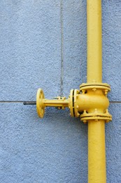 Yellow gas pipe on grey wall outdoors