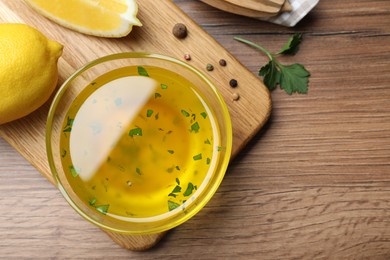 Photo of Bowl of lemon sauce and ingredients on wooden table, flat lay with space for text. Delicious salad dressing