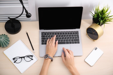 Female blogger using laptop at table, top view. Blank screen for mockup