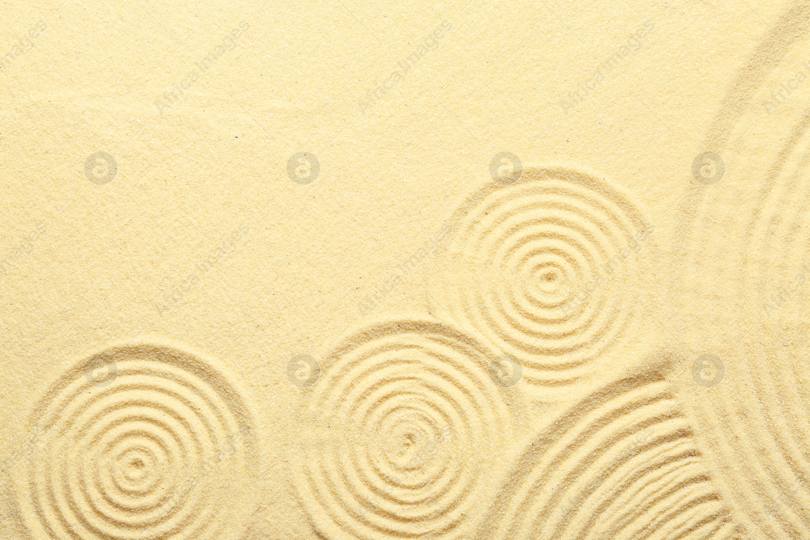 Photo of Zen rock garden. Circle patterns on beige sand, top view