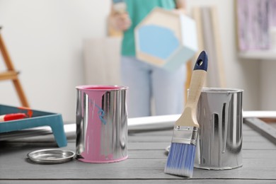 Photo of Cans of paint and brush on grey wooden table indoors