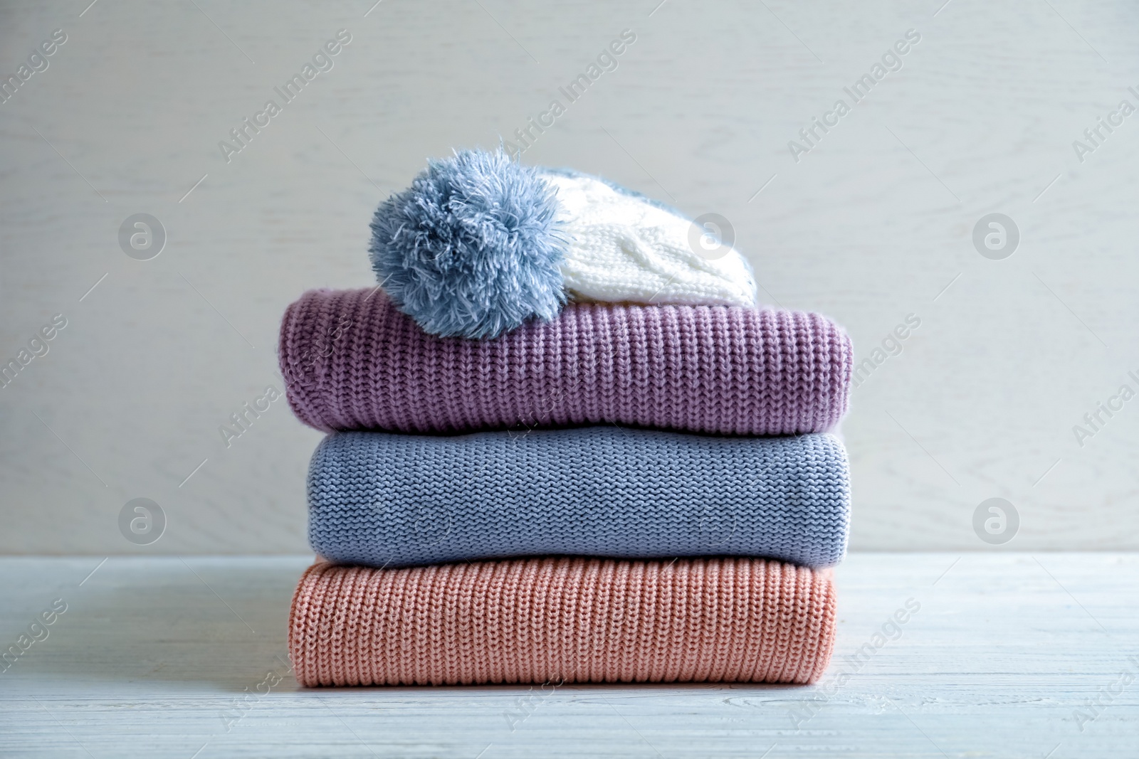 Photo of Stack of warm knitted clothes on table