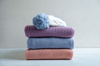 Photo of Stack of warm knitted clothes on table