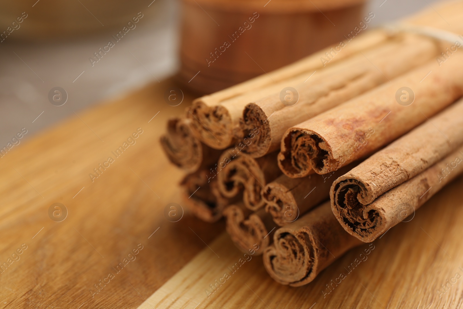 Photo of Aromatic cinnamon sticks on wooden board, closeup