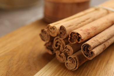 Aromatic cinnamon sticks on wooden board, closeup