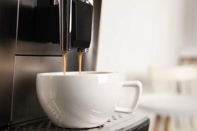 Espresso machine pouring coffee into cup against blurred background, closeup. Space for text