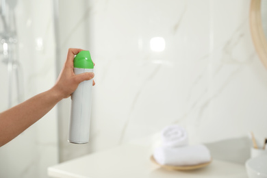 Photo of Woman spraying air freshener in bathroom, closeup