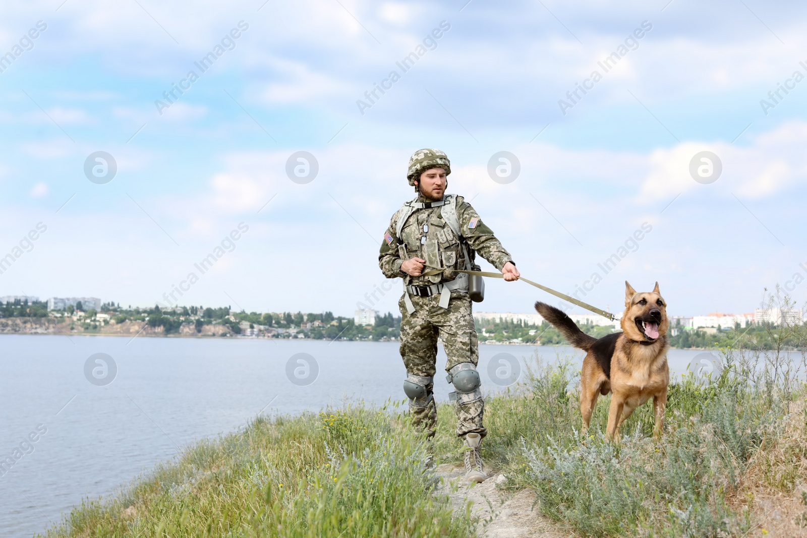 Photo of Man in military uniform with German shepherd dog outdoors