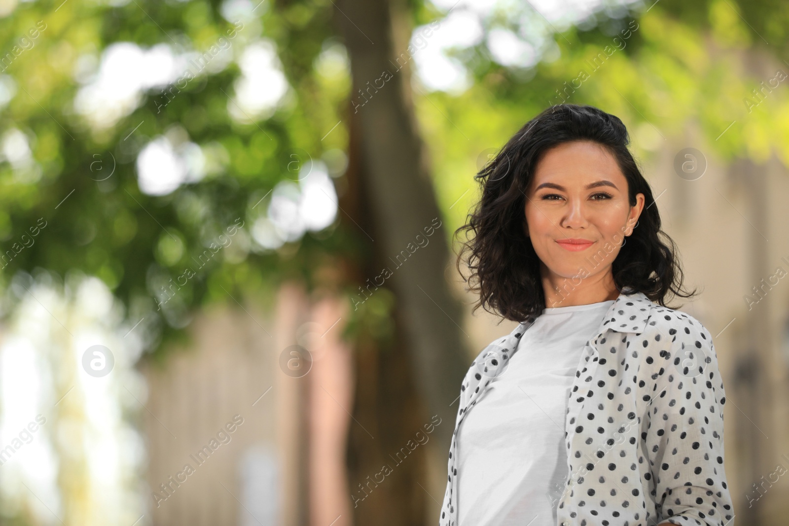 Photo of Happy young woman walking outdoors on sunny day
