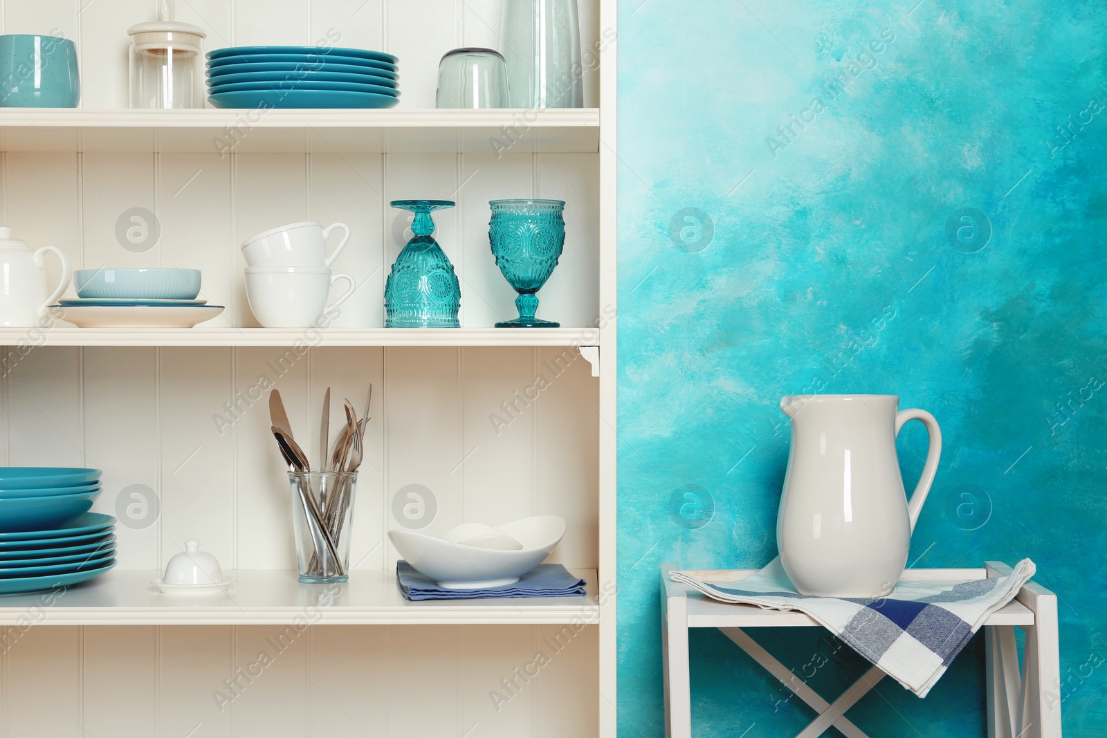 Photo of White shelving unit with set of dishware near color wall