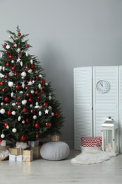 Photo of Beautifully decorated Christmas tree and many gift boxes in room