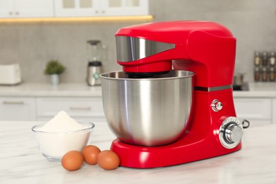 Photo of Modern red stand mixer, eggs and bowl with flour on white marble table in kitchen