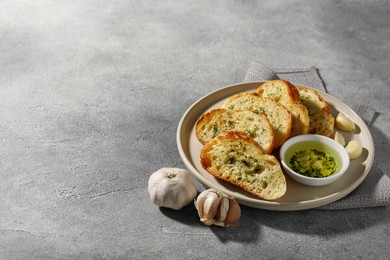 Photo of Tasty baguette with garlic and dill served on grey textured table, space for text