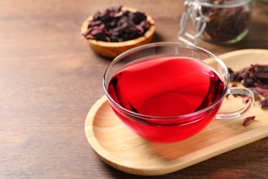 Cup of fresh hibiscus tea on wooden table, closeup. Space for text
