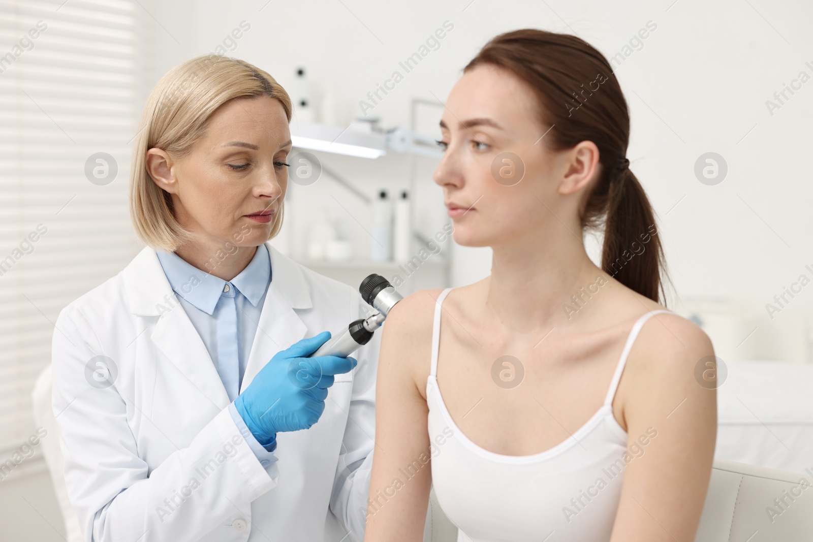 Photo of Dermatologist with dermatoscope examining patient in clinic