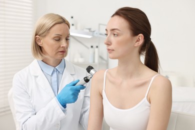 Dermatologist with dermatoscope examining patient in clinic