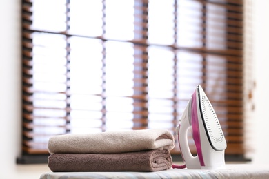 Photo of Modern iron and towels on board in room