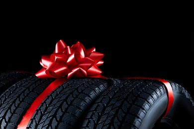 Winter tires with red ribbon on black background, closeup