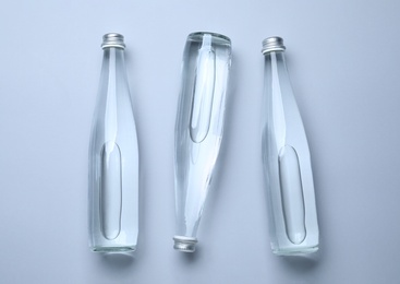Photo of Glass bottles with water on white background, flat lay