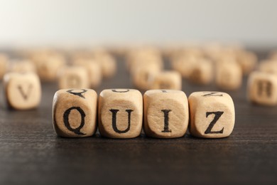 Photo of Cubes with word Quiz on wooden table, closeup