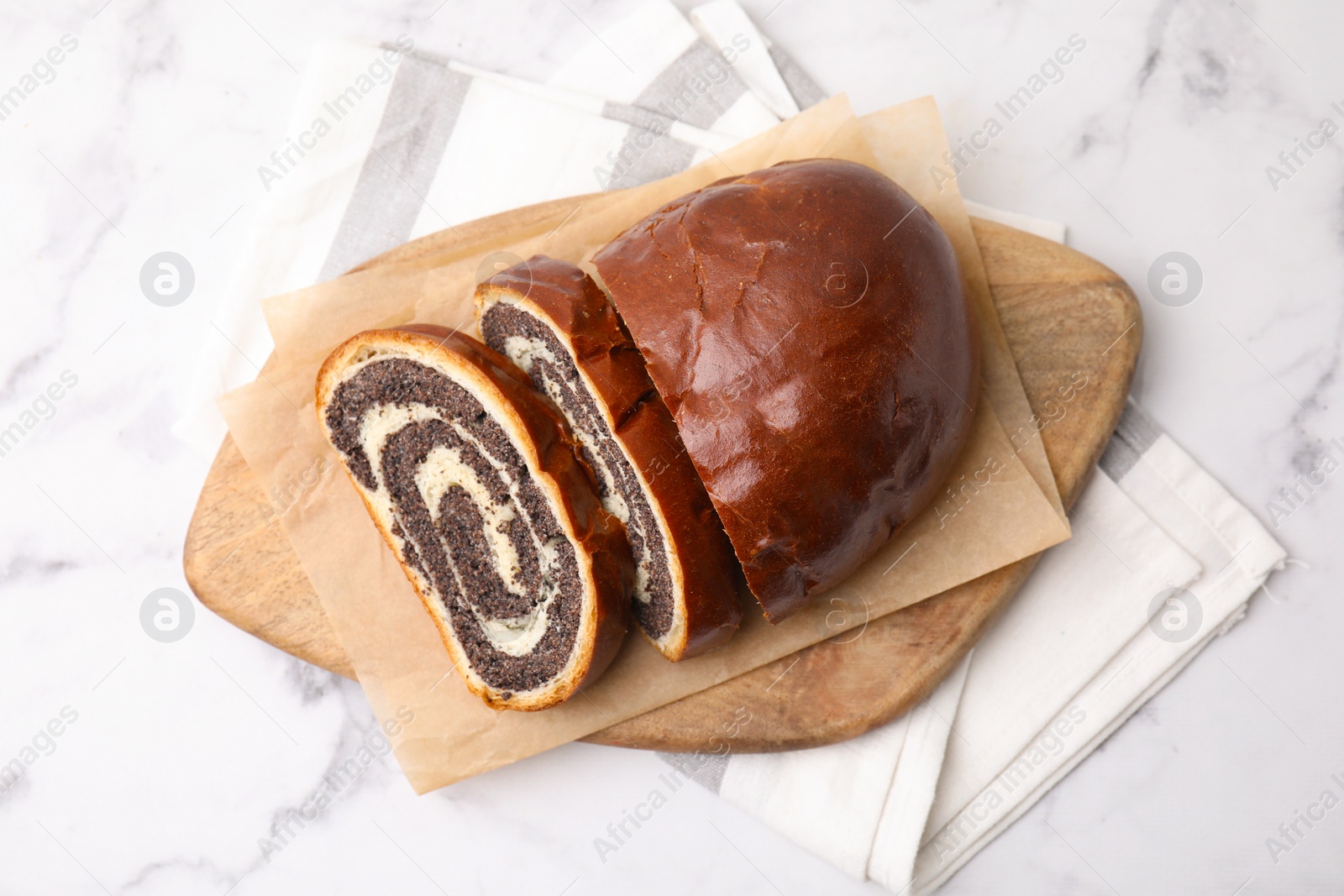 Photo of Cut poppy seed roll on white marble table, top view. Tasty cake