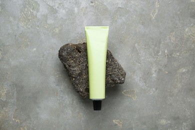 Photo of Tube of hand cream on grey table, top view