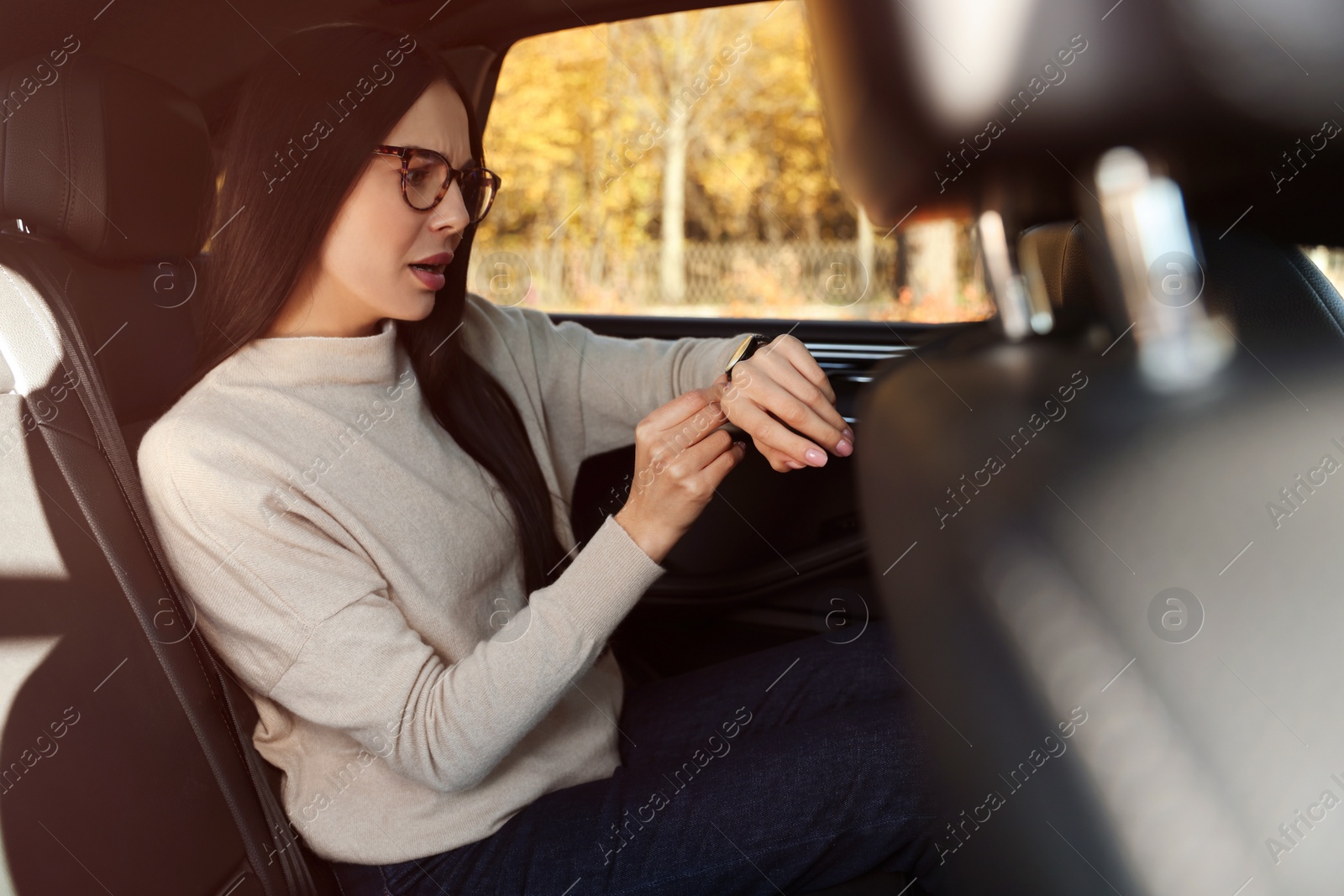 Photo of Emotional woman checking time on watch in car. Being late concept