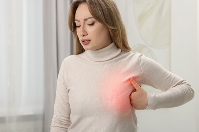 Young woman suffering from breast pain at home