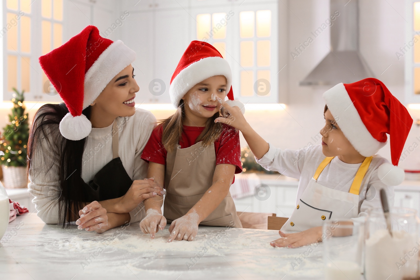 Photo of Mother with her cute little children having fun while making Christmas cookies in kitchen