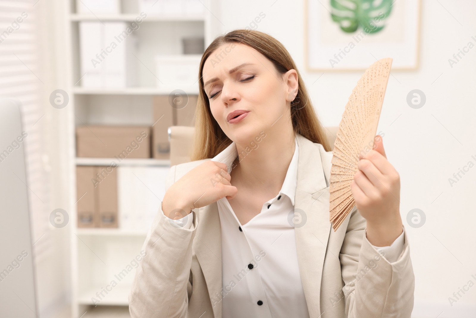 Photo of Businesswoman with hand fan suffering from heat in office