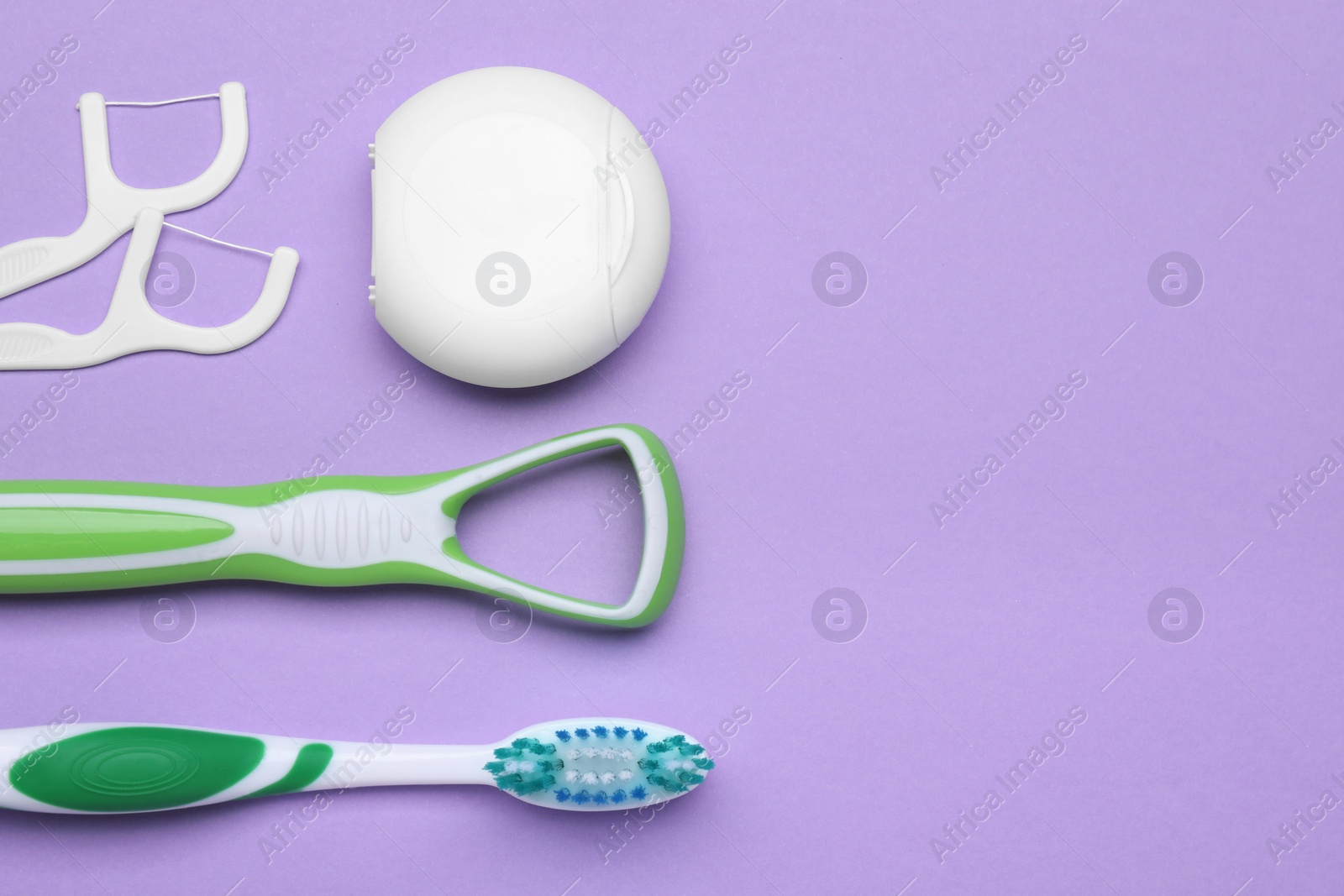 Photo of Tongue cleaner and other oral care products on violet background, flat lay. Space for text