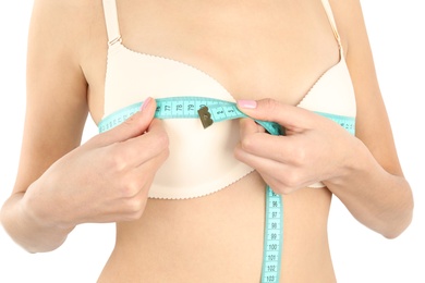 Photo of Young woman measuring breast size on white background, closeup. Cosmetic surgery