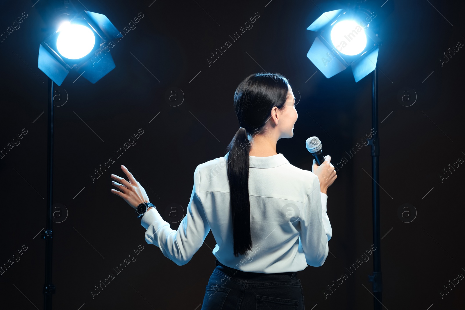 Photo of Motivational speaker with microphone performing on stage, back view