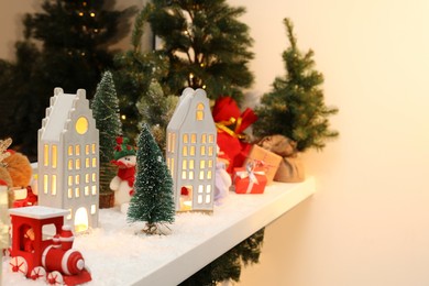 Christmas atmosphere. Beautiful glowing houses, fir trees and toys on window sill indoors. Space for text