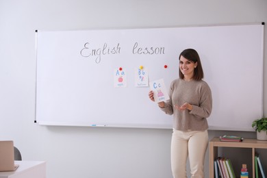 Photo of Happy female English teacher giving lesson indoors. Early childhood education