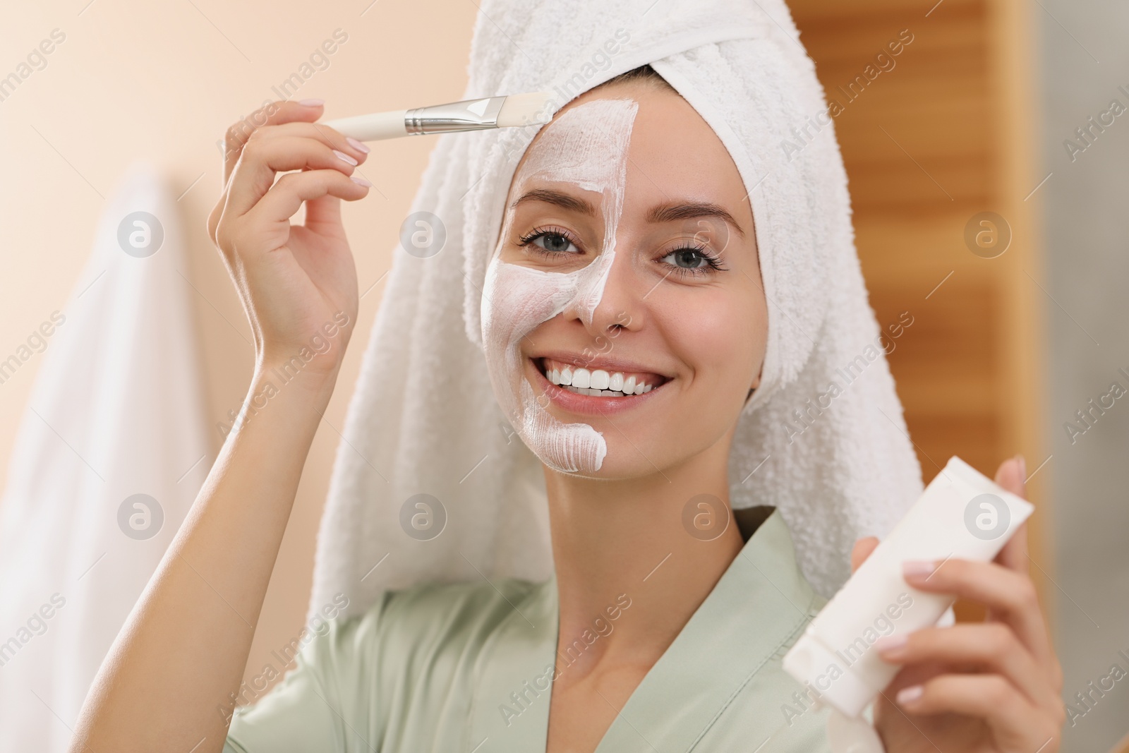 Photo of Woman applying face mask indoors. Spa treatments