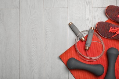 Photo of Flat lay composition with jump rope, gym equipment and space for text on wooden background