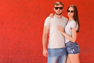 Young couple wearing gray t-shirts near color wall on street