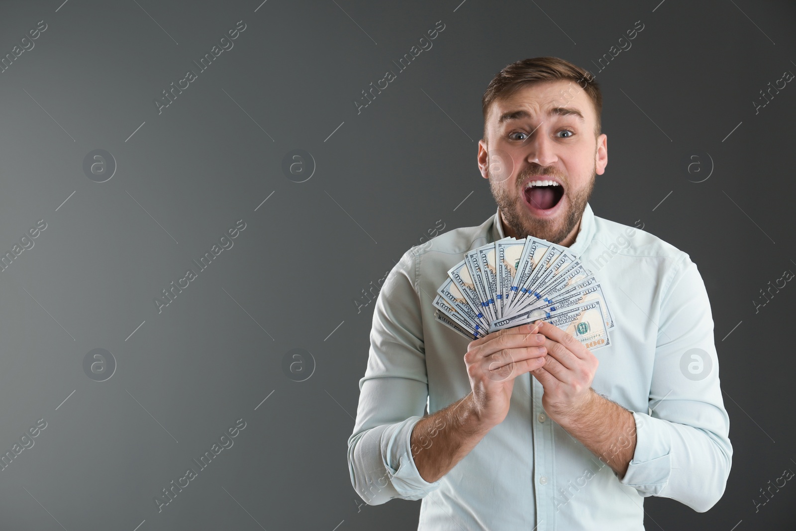 Photo of Portrait of emotional young man with money on grey background. Space for text
