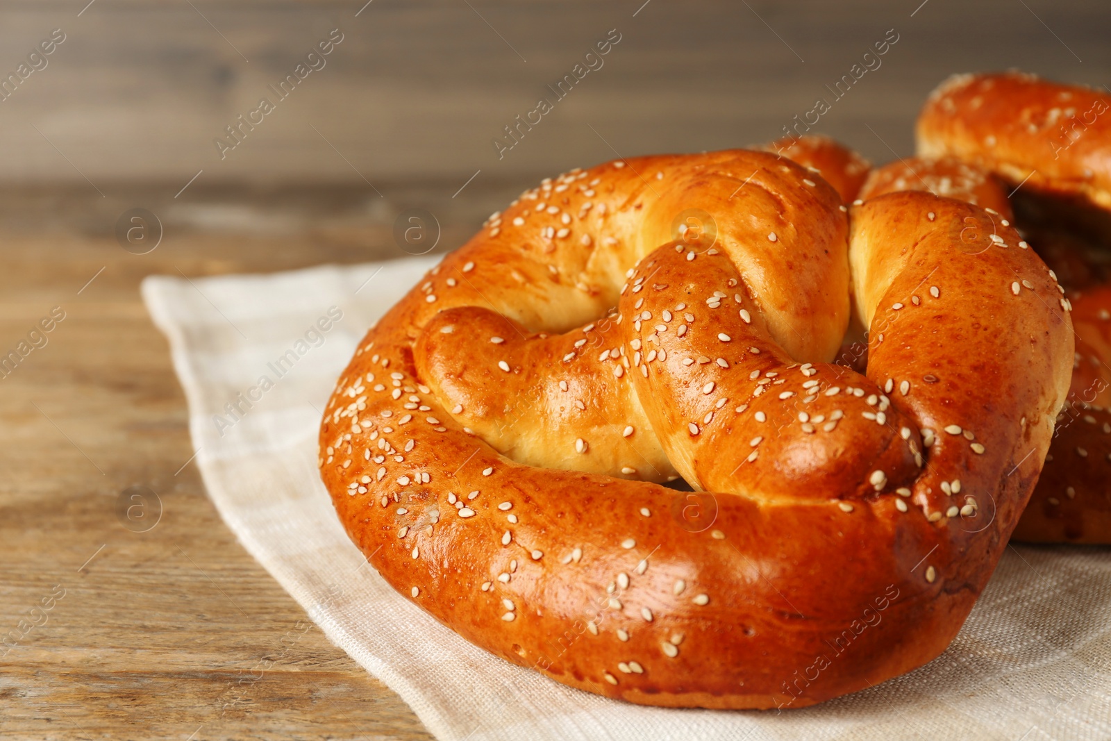 Photo of Tasty freshly baked pretzels on wooden table, closeup view